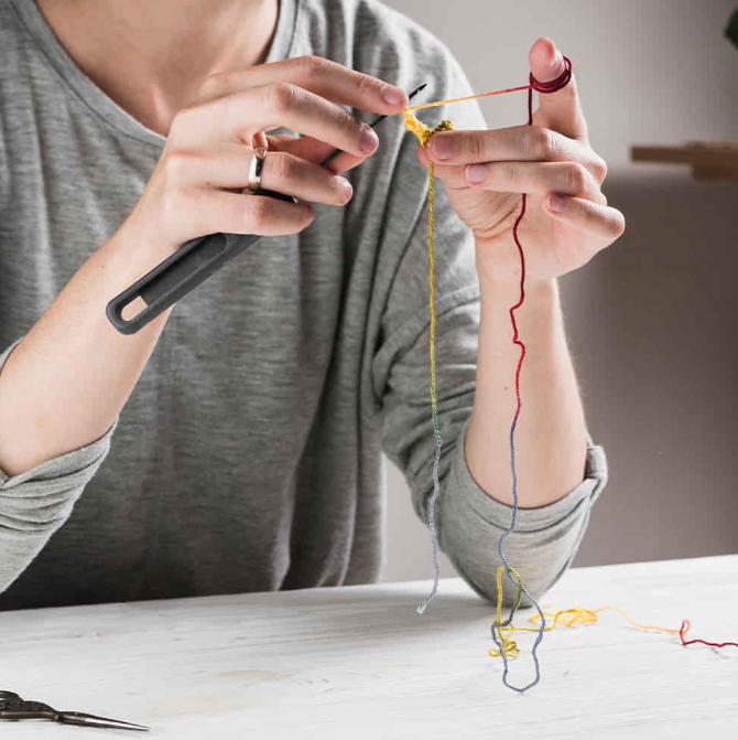Artisan hands craft beautiful, woven-thread jewelry for our collection of zodiac bracelets.